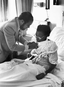 Surgeon Julian Mosley, MD, examines a surgical patient, 1977.